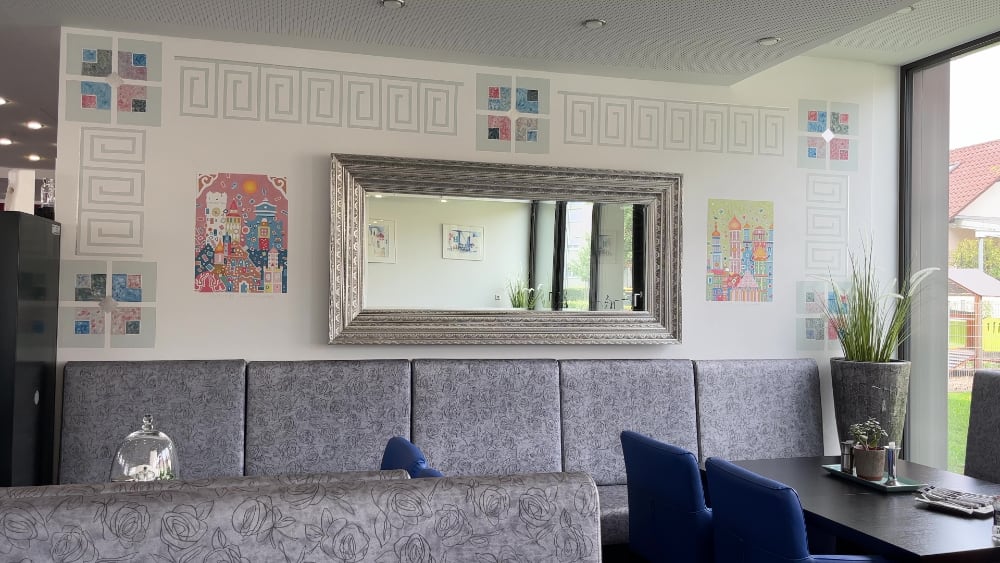 Wandmalerei im Restaurant Konstantinos: griechische Ornamente und Städtebilder rund um einen barocken Spiegel